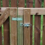 Toggle latch in use to keep brown color wooden fence door locked
